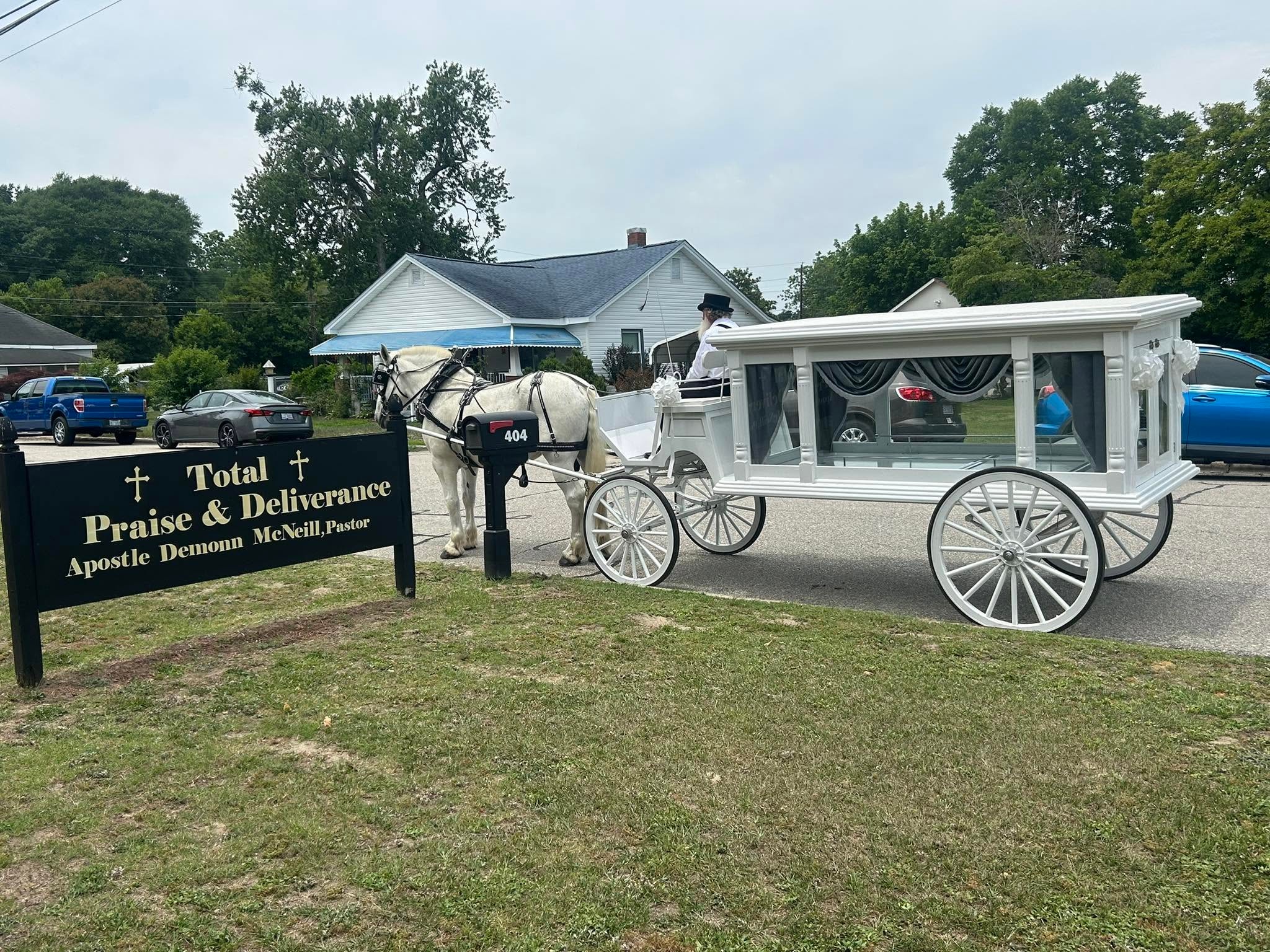 White horse-drawn hearse carriage outside a church